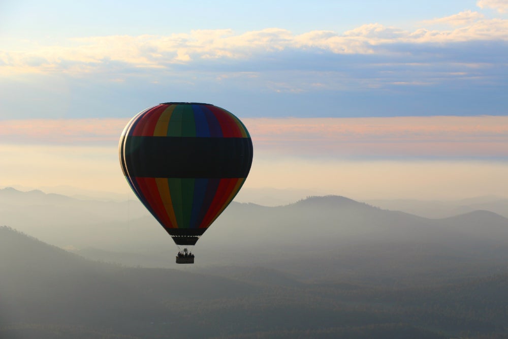 A hot air balloon suspended in mid air with hazy mountains in the background 